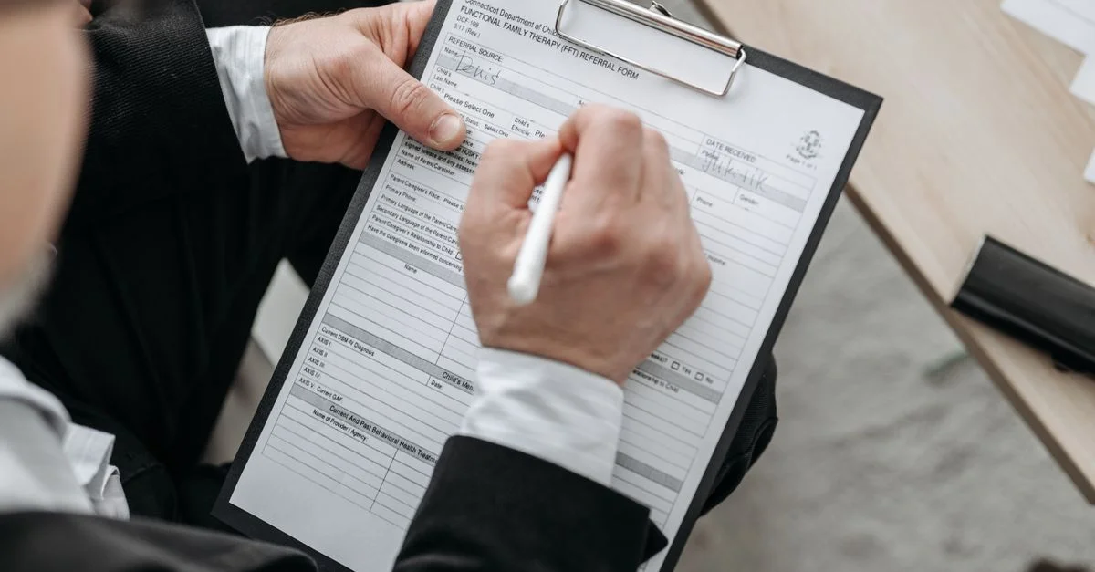 Primer plano de un empresario firmando un documento formal en una carpeta.