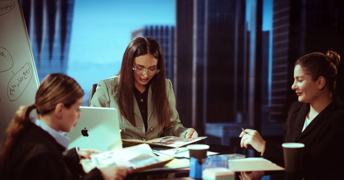 Tres mujeres de negocios participando en una reunión dentro de una oficina contemporánea.