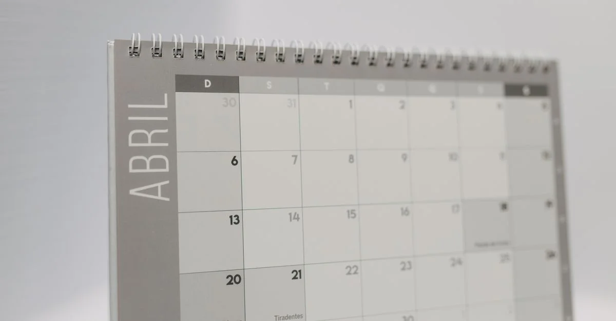 Primer plano de un calendario de mesa de abril encuadernado en espiral con un diseño minimalista en gris.