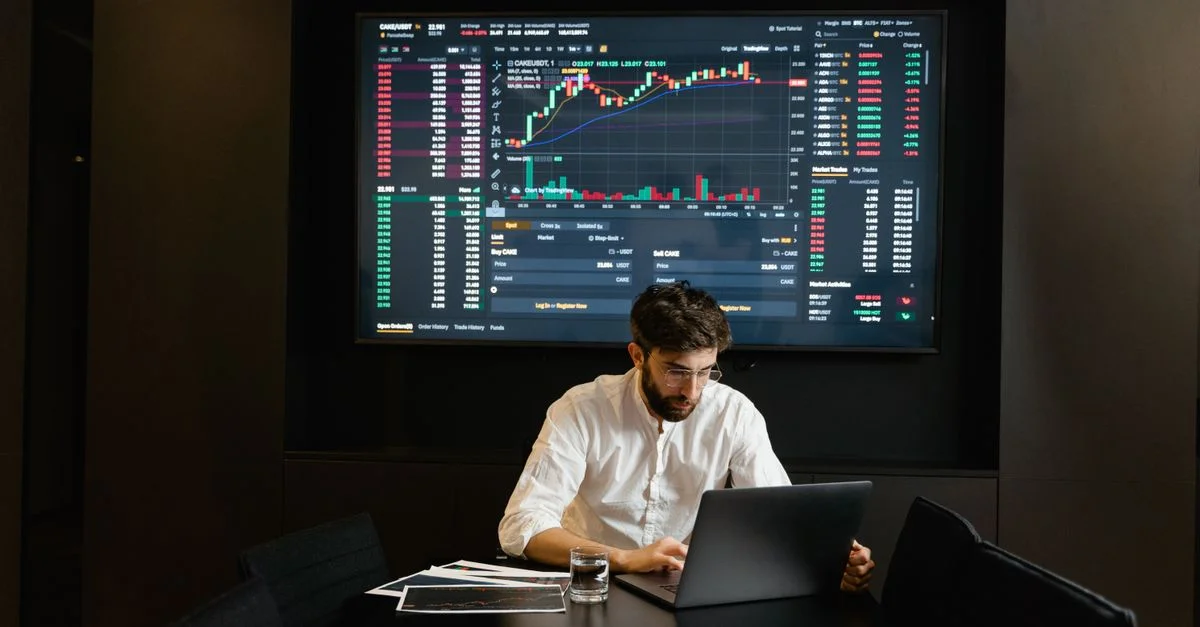 Empresario usando laptop en la oficina analizando gráficos del mercado de valores. Concepto profesional de finanzas e inversiones.