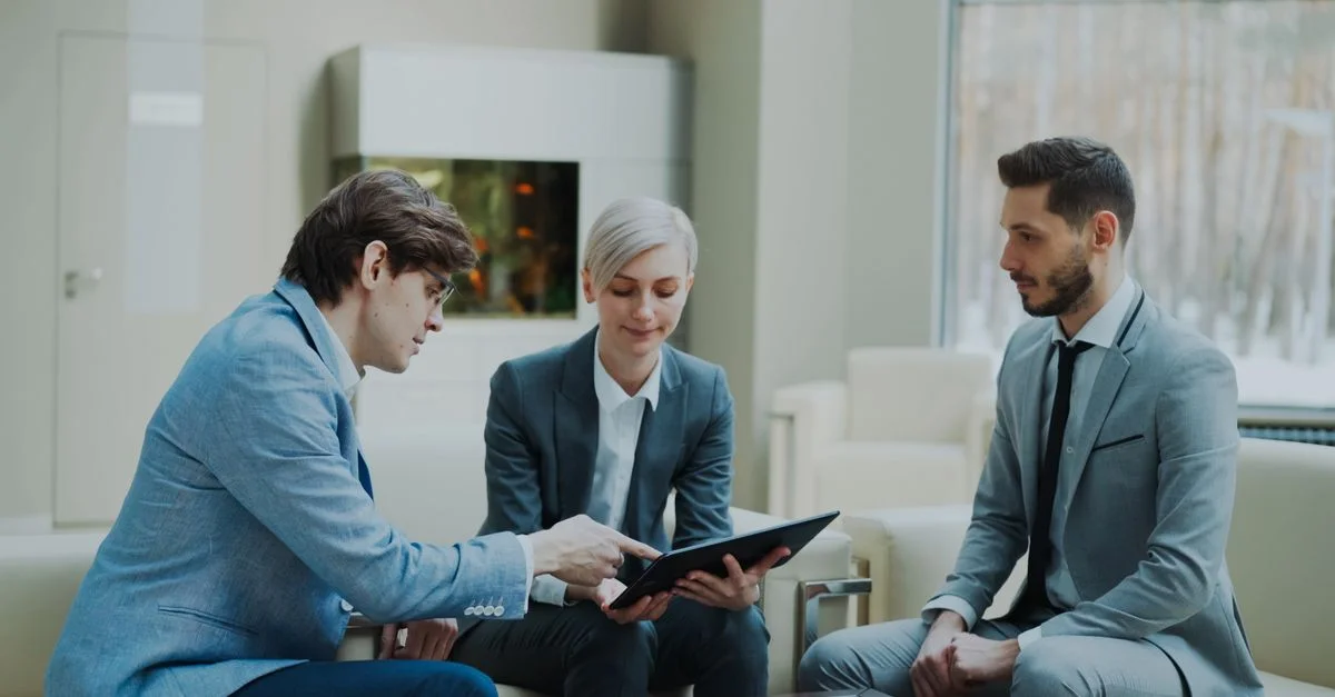 Tres profesionales participando en una reunión de negocios en un entorno de oficina moderna.