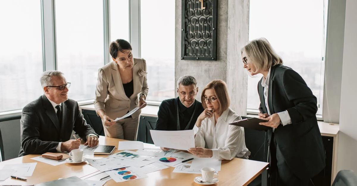 Profesionales de negocios participan en una reunión de oficina para analizar datos y estrategias.