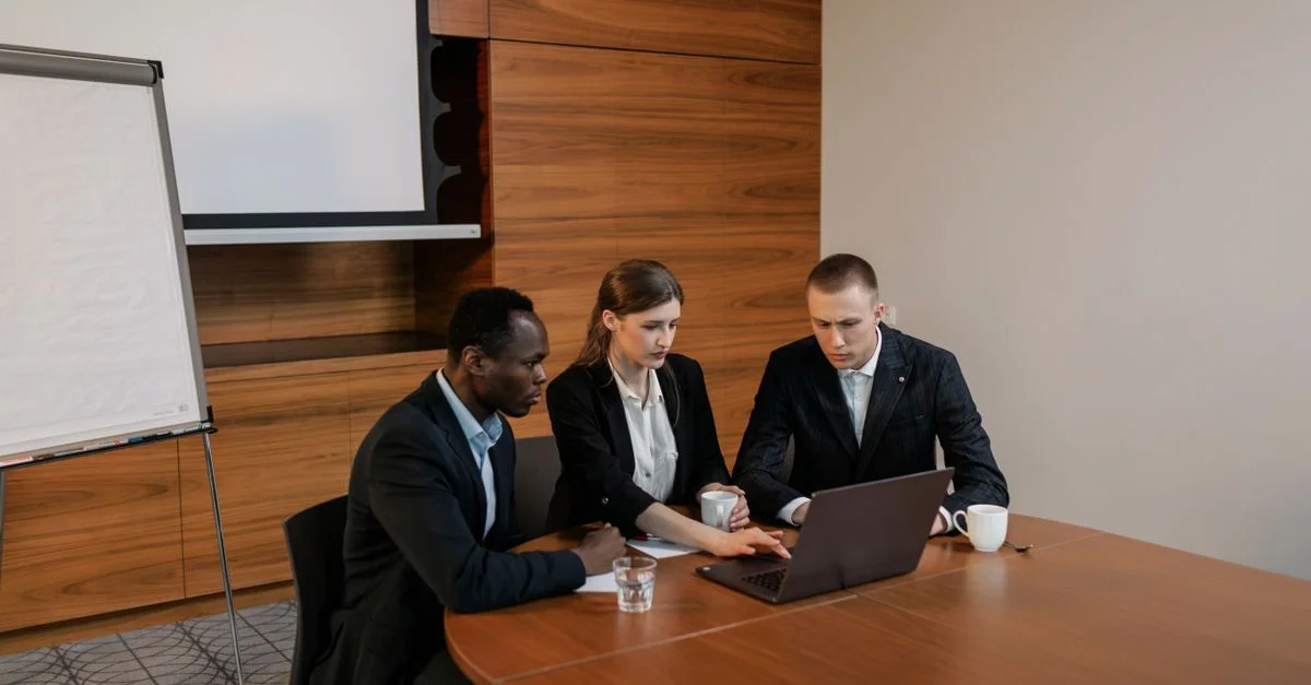 Un grupo de profesionales diversos trabajando juntos en un portátil durante una reunión de oficina en interiores.