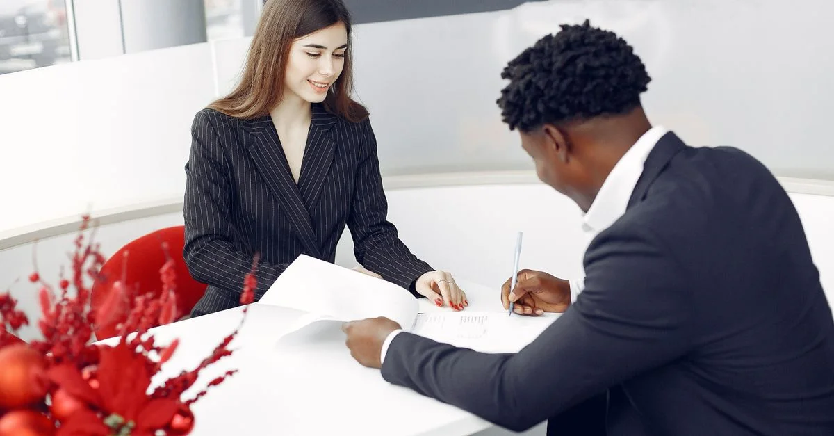 Un entorno profesional con dos personas de negocios firmando un contrato en una oficina.