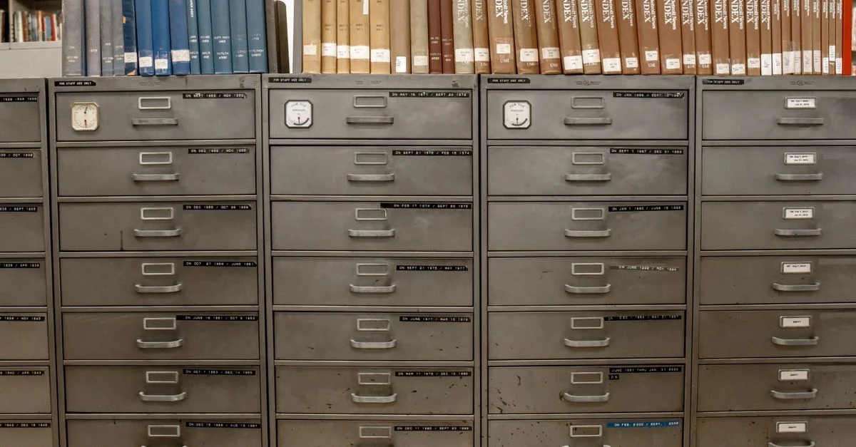 Archivadores organizados apilados con libros indexados en un entorno de biblioteca.