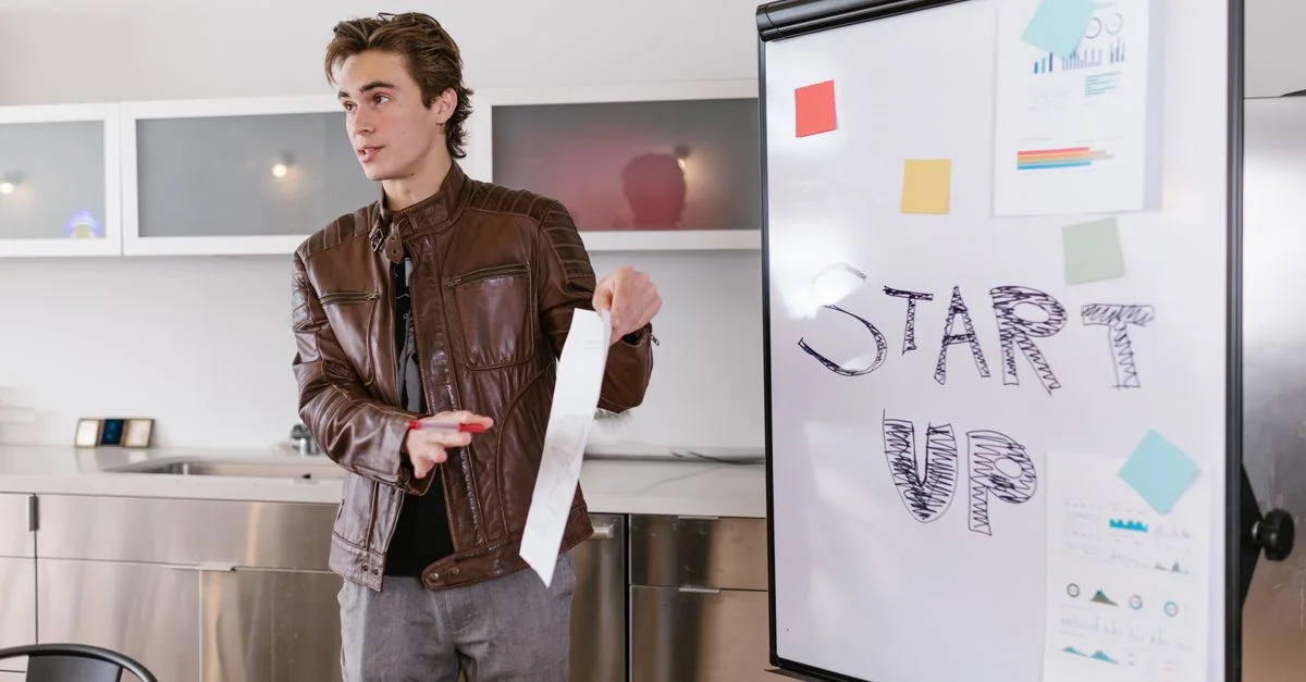 Un joven emprendedor realiza una presentación sobre estrategias de startup en interiores con un rotafolio.