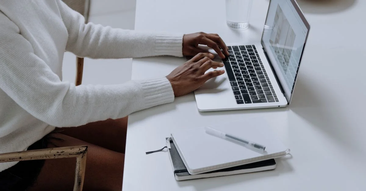 Una persona escribiendo en un portátil en un entorno de oficina minimalista, capturando la cultura laboral moderna.