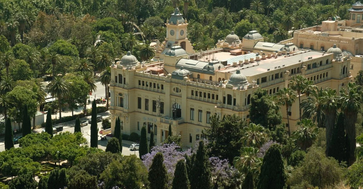 Una pintoresca vista aérea del Ayuntamiento de Málaga, enclavado entre frondosos árboles con la costa de fondo, en la soleada España.