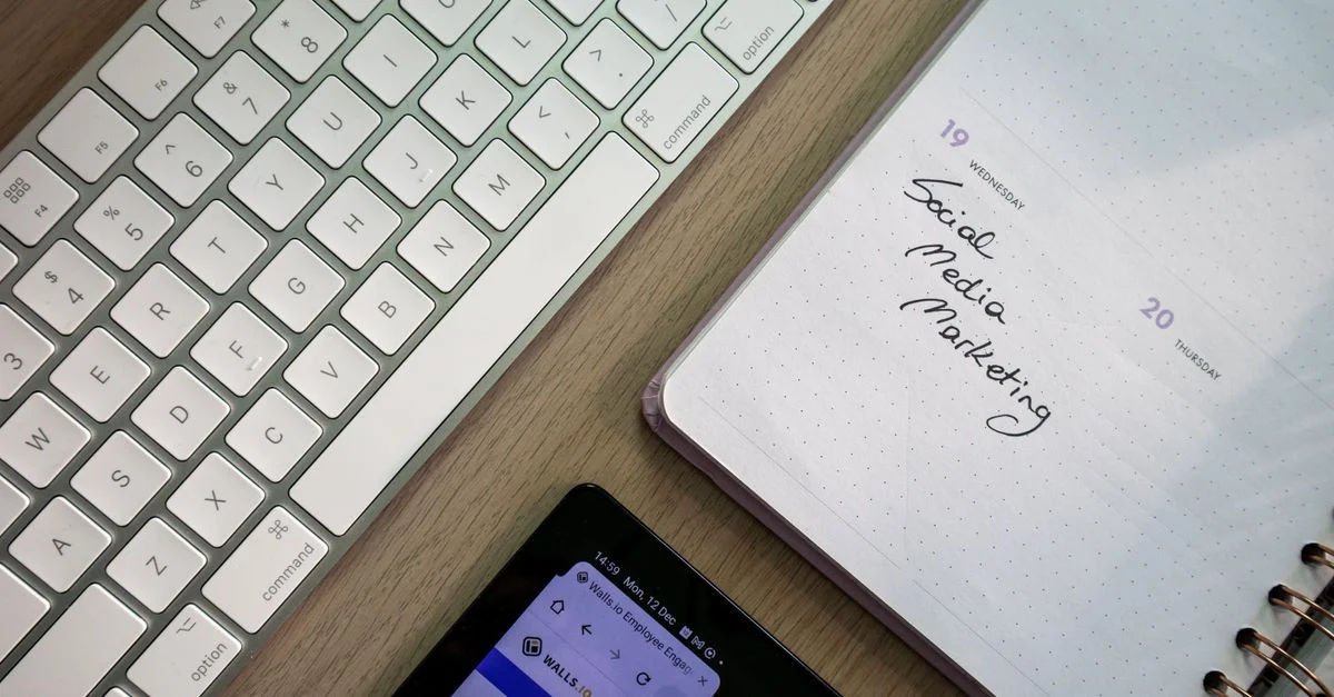 Visión superior del teclado, planificador con nota de marketing en redes sociales y tableta sobre un escritorio.